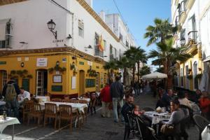 un grupo de personas sentadas en mesas en una calle en Casa Caleta a 2 minutos de la playa, en Cádiz
