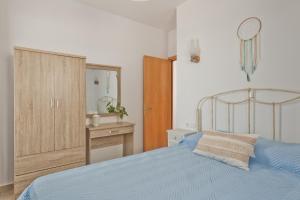 a bedroom with a blue bed and a wooden cabinet at Alisachni Villas in Lefkos Karpathou