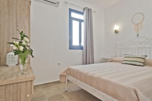 a bedroom with a bed and a vase of flowers on a table at Alisachni Villas in Lefkos Karpathou