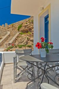 a table and chairs with red flowers on a balcony at Alisachni Villas in Lefkos Karpathou