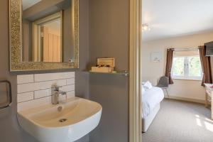 a bathroom with a sink and a mirror and a bed at The Sail Loft in Southwold