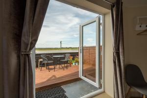 a sliding glass door leading to a deck with a table and chairs at The Sail Loft in Southwold