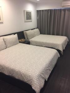 two beds in a hotel room withskirts at Zhongxiao Dunhua Homestay in Taipei
