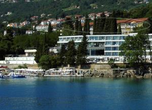 ein großes Gebäude am Ufer eines Wasserkörpers in der Unterkunft Apartments Sonja in Opatija