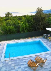 a swimming pool with two lounge chairs next to it at Apartmani Valis in Matulji