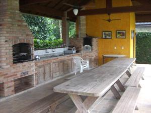 uma cozinha exterior com uma mesa de madeira e uma lareira em Casa Riviera em Riviera de São Lourenço