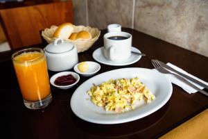 una mesa con un plato de comida y un vaso de zumo de naranja en Hotel El Sol, en Piura