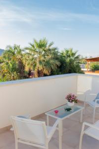 a balcony with chairs and a table and palm trees at Mondello Martini in Mondello