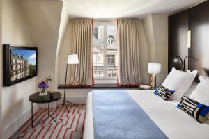a living room with a tv and a bed at Hotel Montalembert in Paris