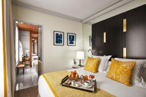 a hotel room with a bed with a tray of food on it at Hotel Montalembert in Paris