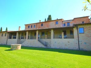 a large brick building with a green lawn in front of it at Luxurious Farmhouse in Montalcino with Pool in Montalcino