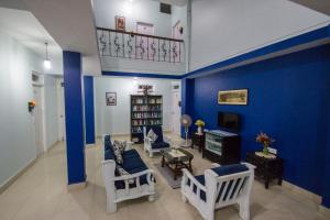 a living room with blue walls and white chairs at Veeniola Holiday Home in Cavelossim