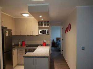 Una cocina con gabinetes blancos y un refrigerador negro. en Departamento Familiar, en Pucón