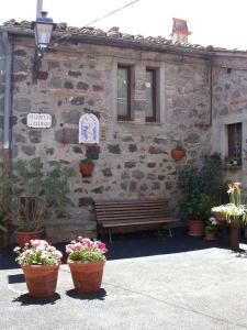 ein Gebäude mit einer Bank und Blumen davor in der Unterkunft Casa del Ciliegio in Radicofani