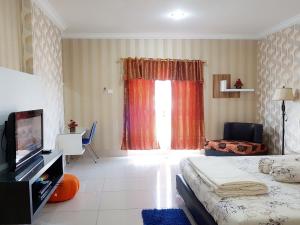 Schlafzimmer mit einem Bett, einem TV und einem Fenster in der Unterkunft Apartemen MTC 623 in Manado