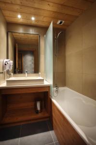 a bathroom with a tub and a sink and a mirror at Résidence Les Arolles by Les Etincelles in Arc 2000