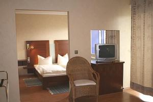 Zimmer mit einem Bett, einem TV und einem Stuhl in der Unterkunft Hotel Wadegotia in Wadgassen