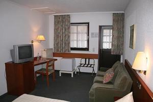 un soggiorno con divano, scrivania e TV di Hotel Wadegotia a Wadgassen
