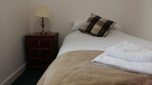 a bed with white sheets and a pillow and a night stand at Clarence Road Apartment in Gosport