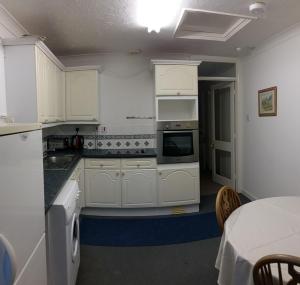 eine Küche mit weißen Schränken und einem Tisch darin in der Unterkunft Clarence Road Apartment in Gosport