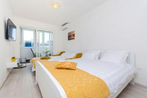 ein weißes Schlafzimmer mit einem großen Bett und einer gelben Decke in der Unterkunft Super amazing apartments in Split