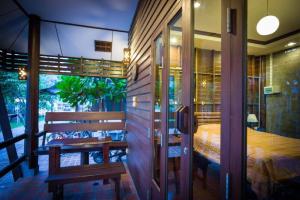 a bedroom with a bed and a bench on a balcony at Ruenpurksa Resort in Prachuap Khiri Khan