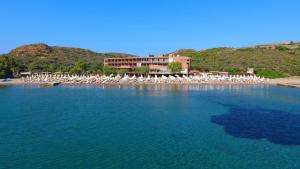 a beach with chairs and umbrellas in the water at Aegeon Beach Hotel in Sounio