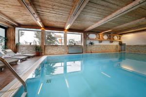 a swimming pool in a house with a wooden ceiling at Hotel Alpenblick in Pfelders