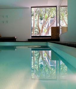 a swimming pool with a reflection of a palm tree at Family Secrets Santo André in Santa Maria Da Feira