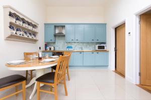 a kitchen with blue cabinets and a table and chairs at 2 Suffolk Cottage, Knodishall in Aldringham