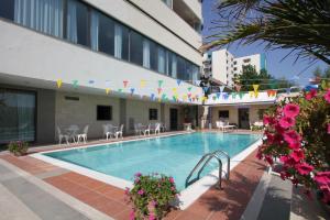 een zwembad in een hotel met vlaggen en bloemen bij Hotel Promenade in Montesilvano