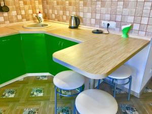 ドミトロフにあるАпартаменты на Школьнойのキッチン(緑のキャビネット、木製テーブル、スツール付)