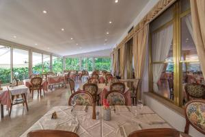 a dining room with tables and chairs and windows at Hotel Verdemare in Marina di Pietrasanta
