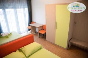 a room with a bed and a desk and a door at Vila Evergreen 2 Mai in 2 Mai