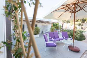 a patio with purple chairs and an umbrella at Marina Loft Sicily in Marina di Ragusa