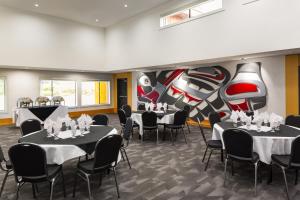 uma sala de jantar com mesas e cadeiras e um mural em Kwa'lilas Hotel em Port Hardy
