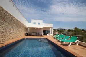 una piscina con sillas verdes y una casa en Elena Baladrar - sea view villa with private pool in Benissa, en Benissa