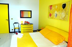 a yellow bedroom with a bed and a dresser at Il Gatto e La Volpe in Venetico