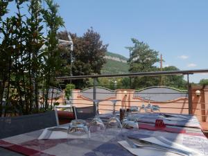 einen Tisch mit Weingläsern und Servietten auf dem Balkon in der Unterkunft Cévenol Hôtel in Millau