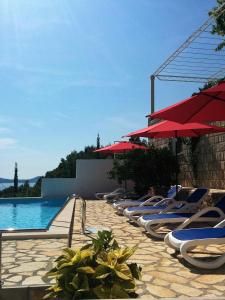 a row of lounge chairs and umbrellas next to a pool at Apartments Anamaria in Dubrovnik