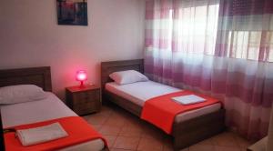 two twin beds in a room with a red lamp at Roses RT apartments Skioni I in Nea Skioni
