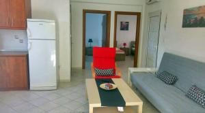 a living room with a couch and a refrigerator at Roses RT apartments Skioni I in Nea Skioni +15 photos