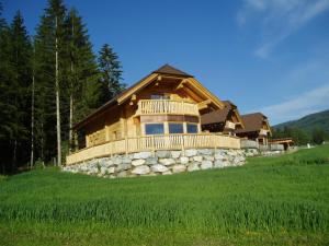 eine Blockhütte auf einem Hügel mit einer Steinmauer in der Unterkunft Alpenchalets Weissenbacher in Tamsweg