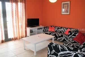a living room with a couch and a tv at Lanzarote Green Villas in Playa Blanca
