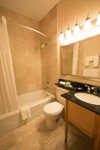 a bathroom with a toilet and a sink and a tub at Adria Hotel and Conference Center in Queens