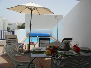 a table and chairs with an umbrella and a pool at Aloha 45 in Playa Blanca