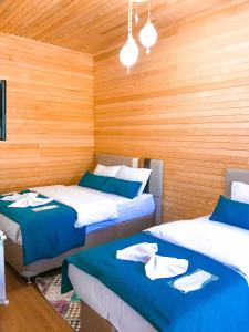two beds in a room with wooden walls at Mego Suite Otel in Uzungöl