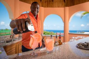 een man die een drankje uit een fles schenkt bij Villa Sweet Villa - Montego Bay in Montego Bay