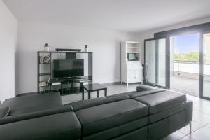 a living room with a black couch and a television at Le 180° in Montpellier