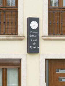 a sign on the side of a building with a clock at Pension Rustica Casa Do relojero in Zas